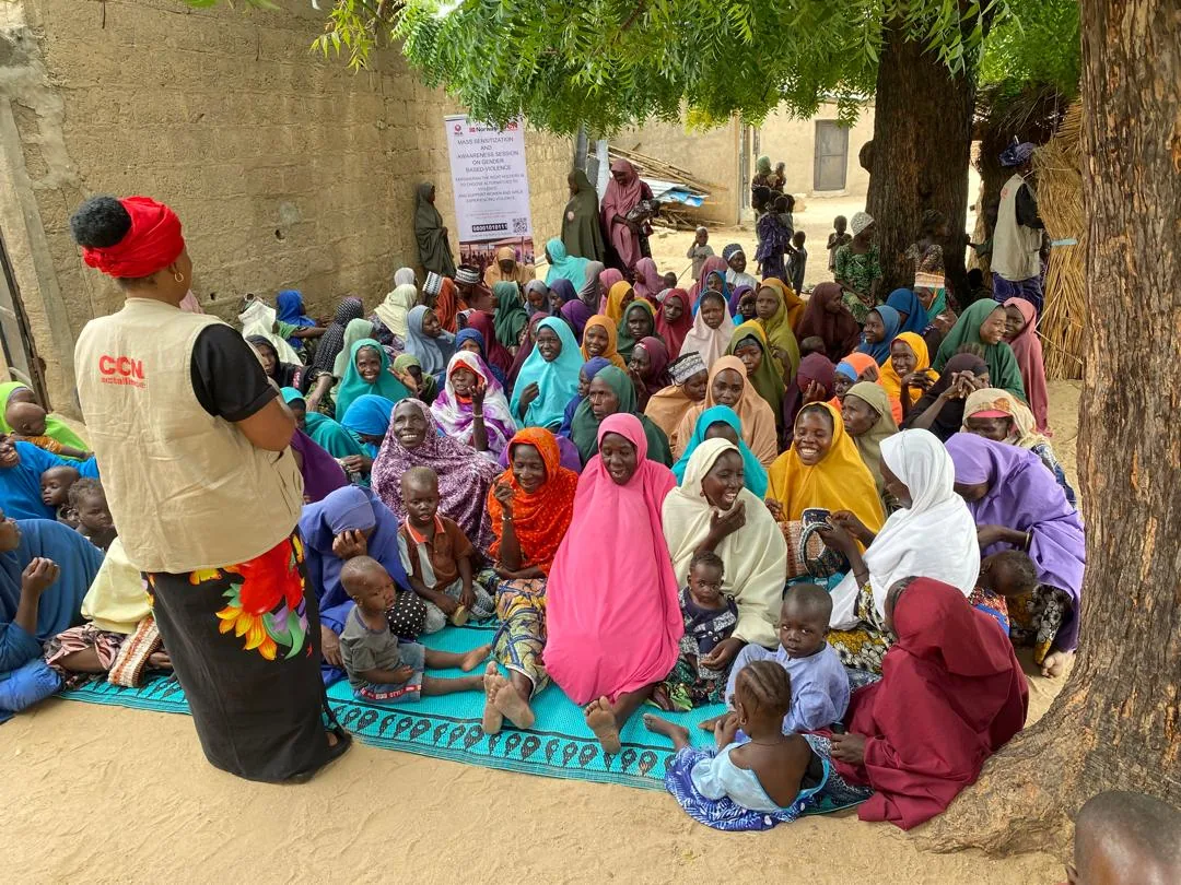 People listening to a facilitator beneath a tree