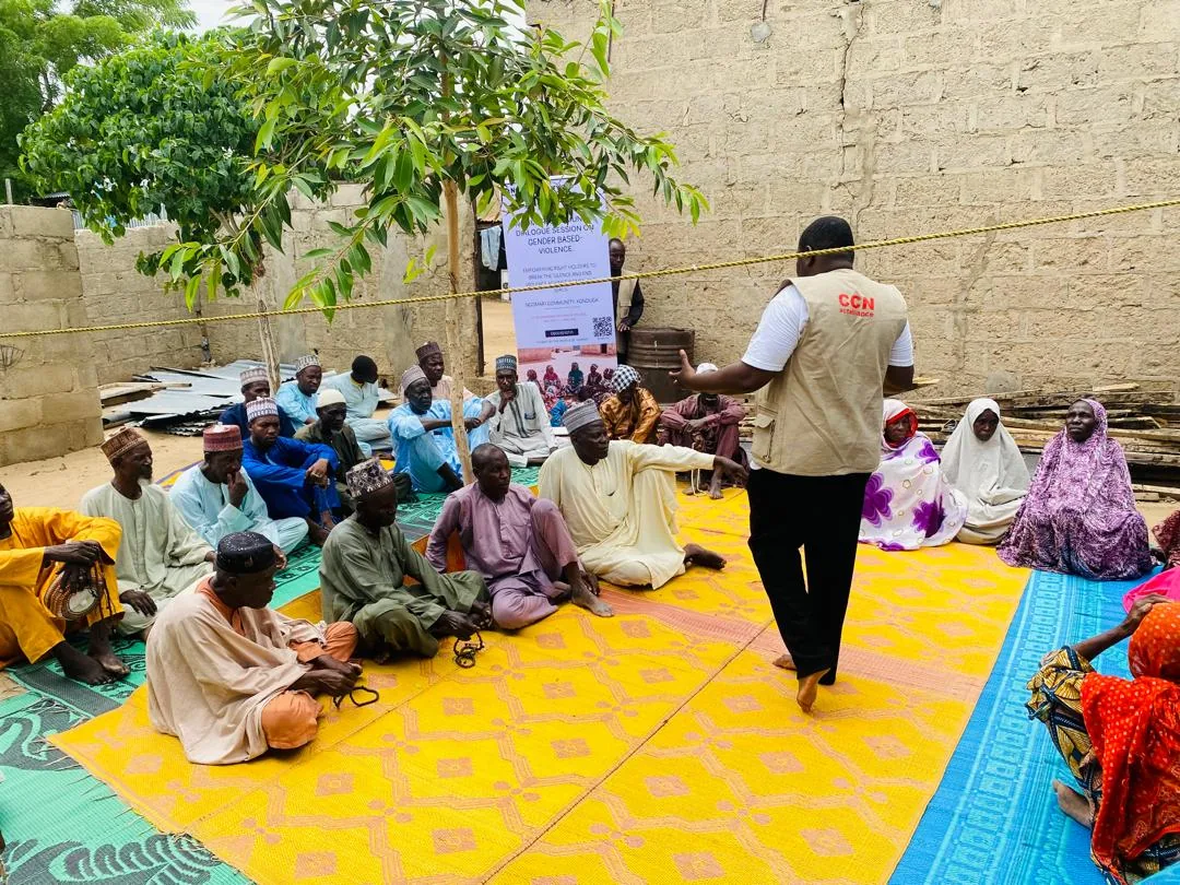 A facilitator standing beside a seated outdoor group